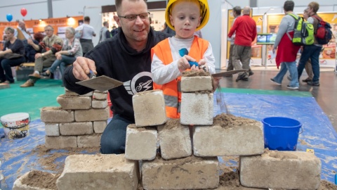 Ein Vater braut mit seinem Kind eine Mauer aus Stein. Ein Vater braut mit seinem Kind eine Mauer aus Stein.