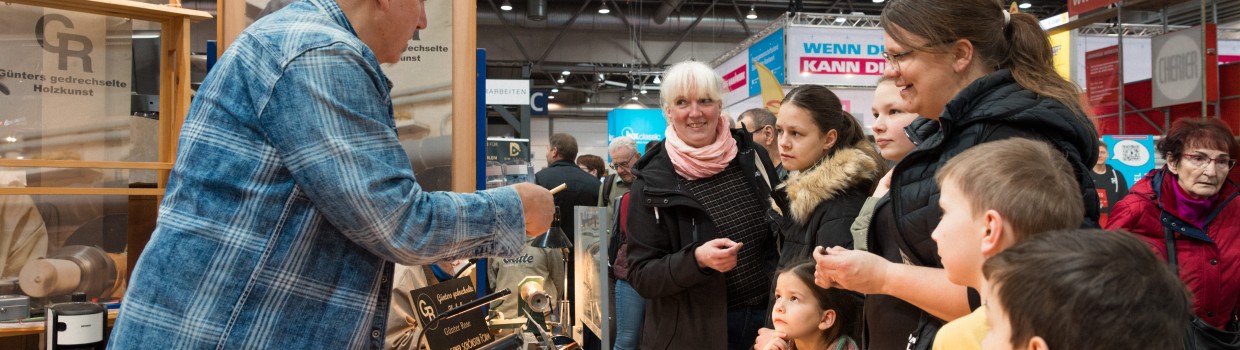 2 Frauen und eine Gruppe von Kindern stehen an einem Verkaufsstand für Werkzeuge. Ein Mann berät die Gruppe. 2 Frauen und eine Gruppe von Kindern stehen an einem Verkaufsstand für Werkzeuge. Ein Mann berät die Gruppe.